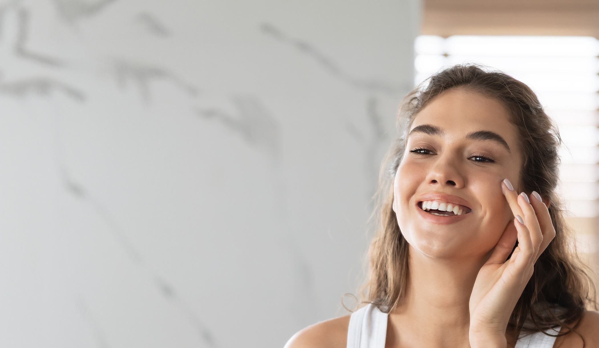 Young woman looking at her face in a mirror after aesthetic skin treatment in Panama City