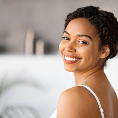 a woman smiling with glowing and youthful skin