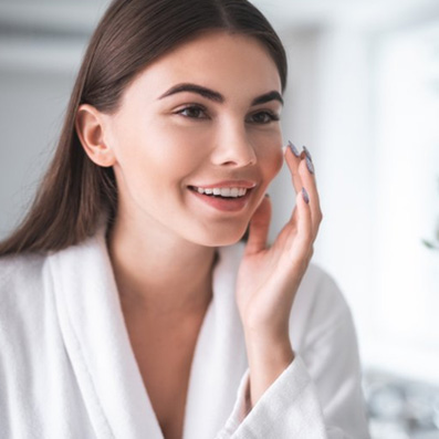 a woman smiling and touching her youthful face