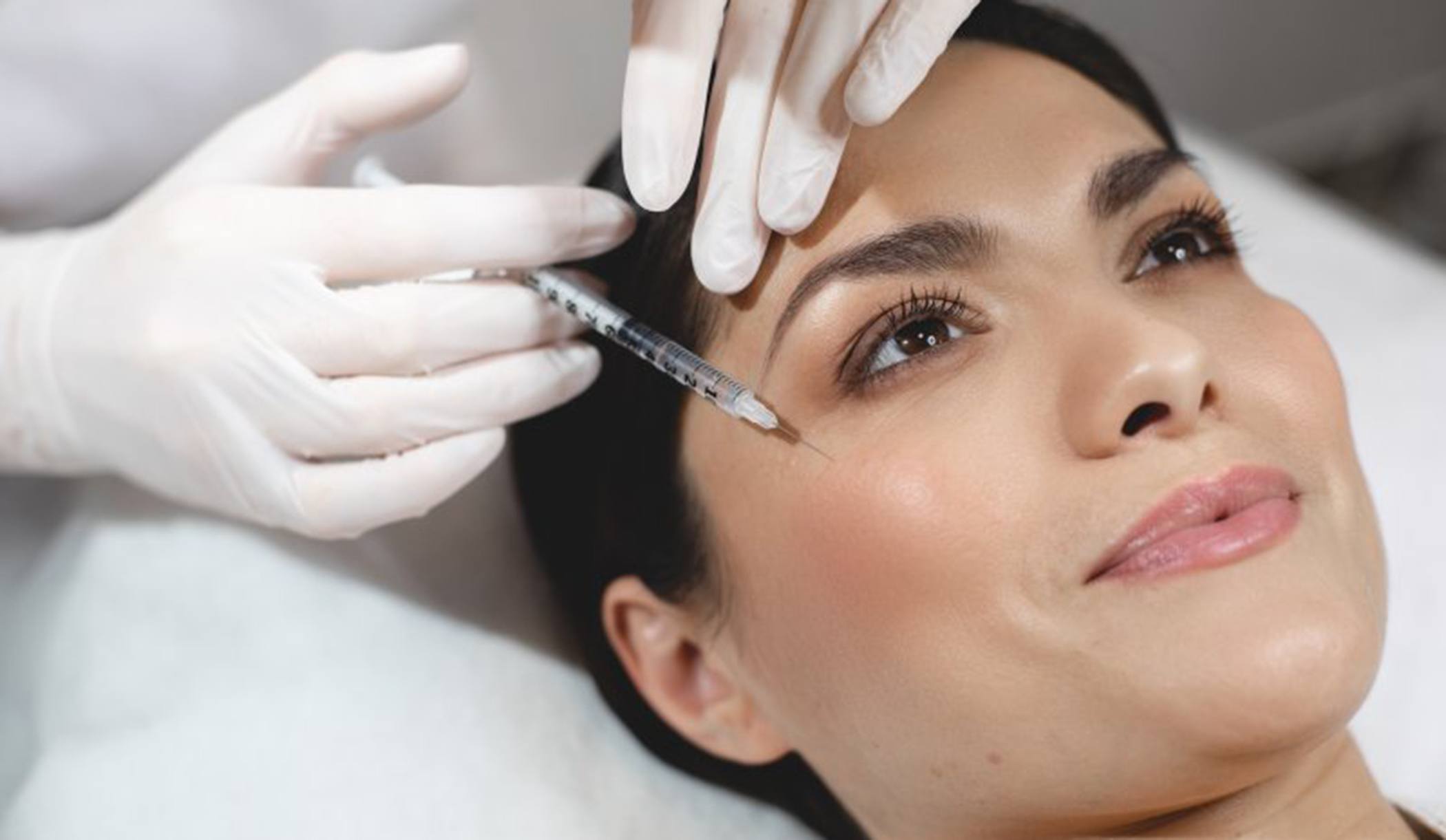 a woman smiling while receiving BOTOX injections