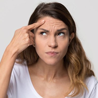 a woman pointing at wrinkles on her forehead
