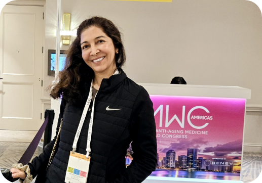 Doctor Azam smiling in front of a sign for the American Academy of Anti Aging Medicine